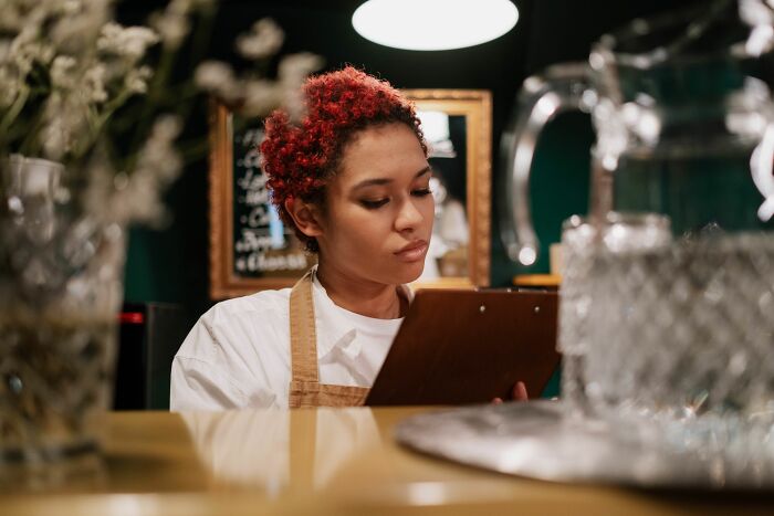 Restaurant worker reviewing order details on clipboard behind the counter