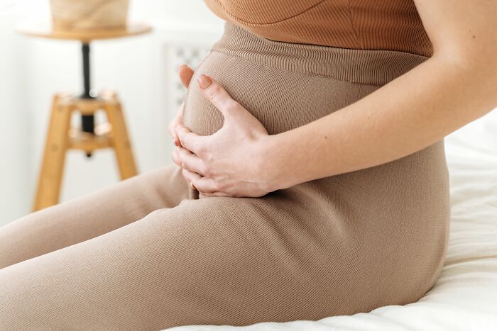 A pregnant woman holding her belly, experiencing common health symptoms during pregnancy.