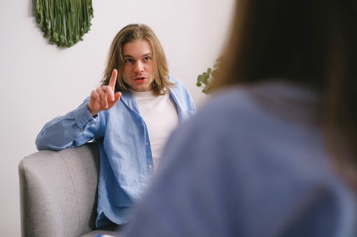Man points his finger, possibly expressing a complaint about his dinner or a need for hot tea.