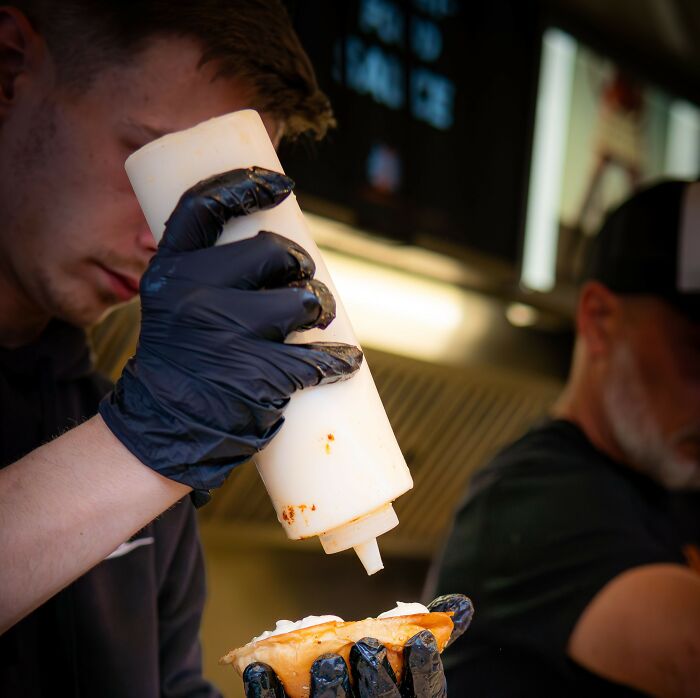 Restaurant chef squeezing sauce on food wearing black gloves