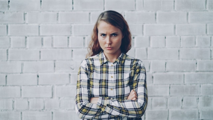 Angry woman with arms crossed representing mom crashing trip