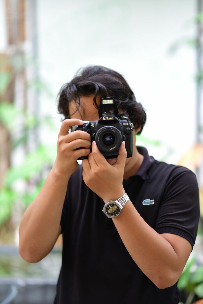 Man taking a photo with a Nikon camera, a simple joy that has become mainstream.