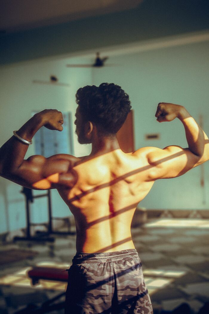 A bodybuilder showing off his back muscles, highlighting childhood beliefs about strength and physique.