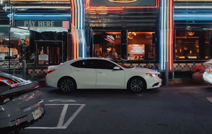 White car parked outside a brightly lit restaurant at night