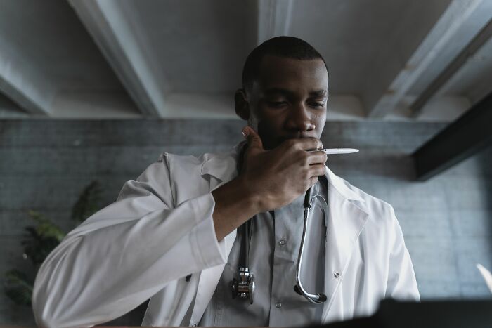 A thoughtful male doctor in a white coat and stethoscope, contemplating health symptoms that terrify doctors.