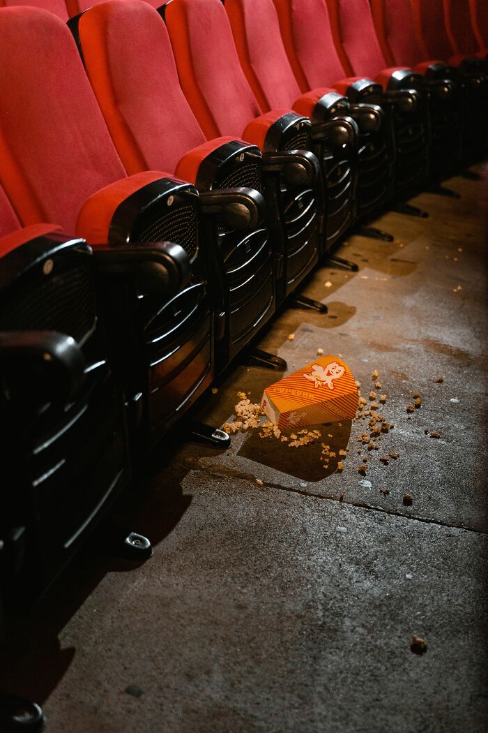An overturned popcorn box with spilled popcorn on a cinema floor, representing dating red flags.