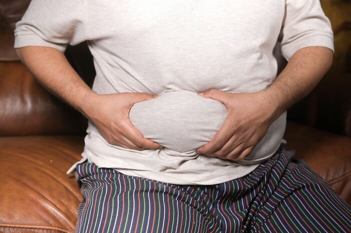 Man clutching his belly fat, a visual representation of stereotypes about the US and its population's health.