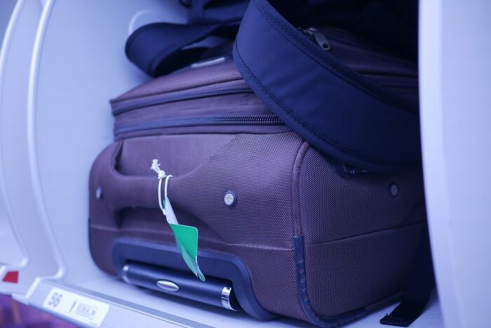 Brown luggage stored securely inside a plane overhead bin