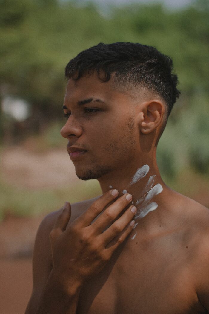 A young man applies sunscreen to his neck, demonstrating how daily actions can cause different pain reactions.