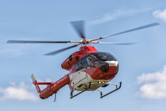 Red and white helicopter from AIR LLOYD in flight against a blue sky, showcasing industry secrets.