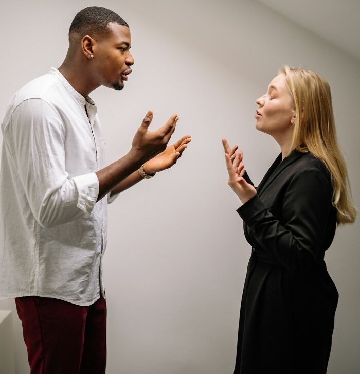A man and woman arguing, gesturing with their hands, showing tension after a meal of dinner and hot tea.
