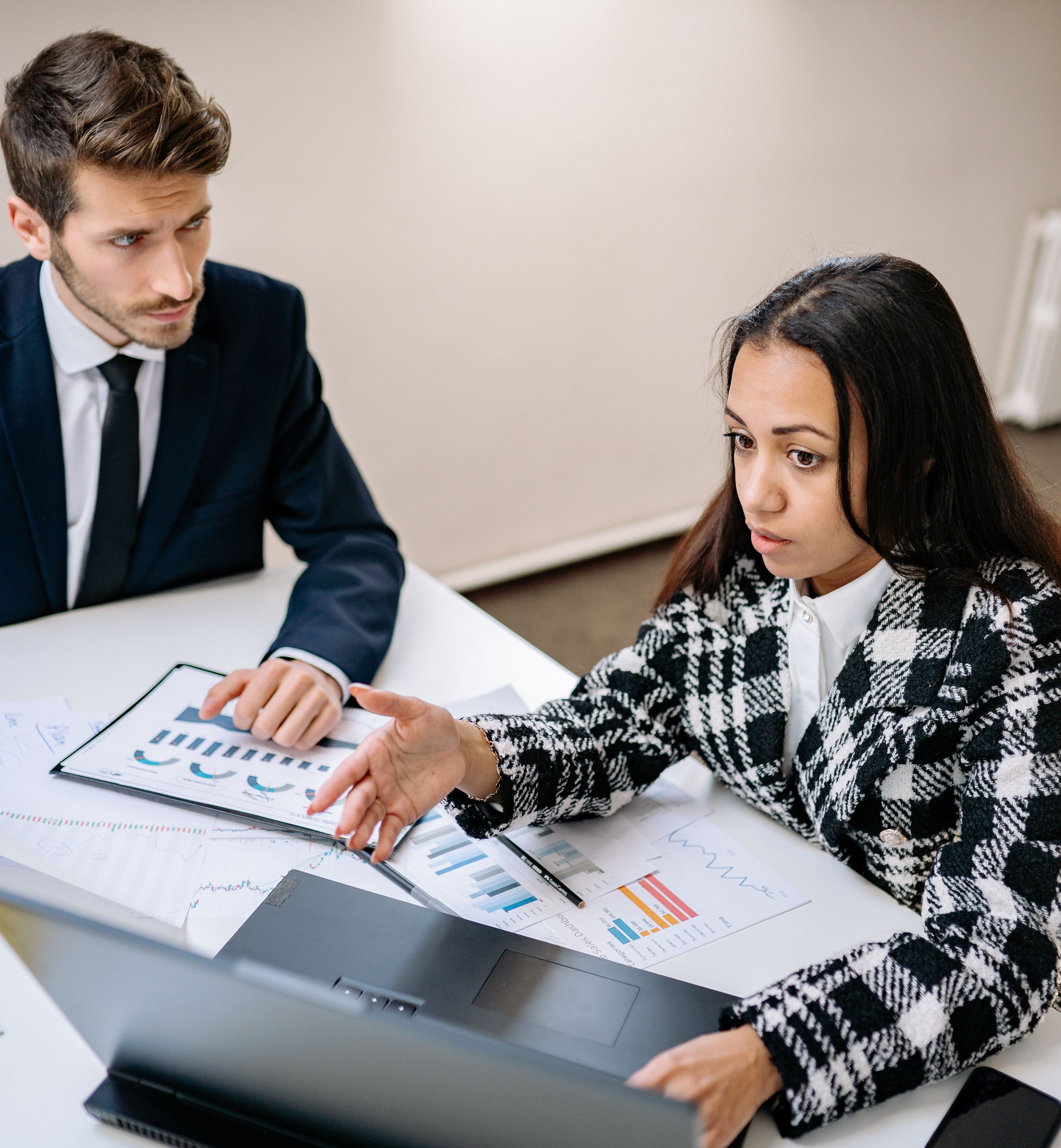A mentor talking to a male colleague, pointing at a laptop while discussing a potential gender-biased complaint. A mentor talking to a male colleague, pointing at a laptop while discussing a potential gender-biased complaint.