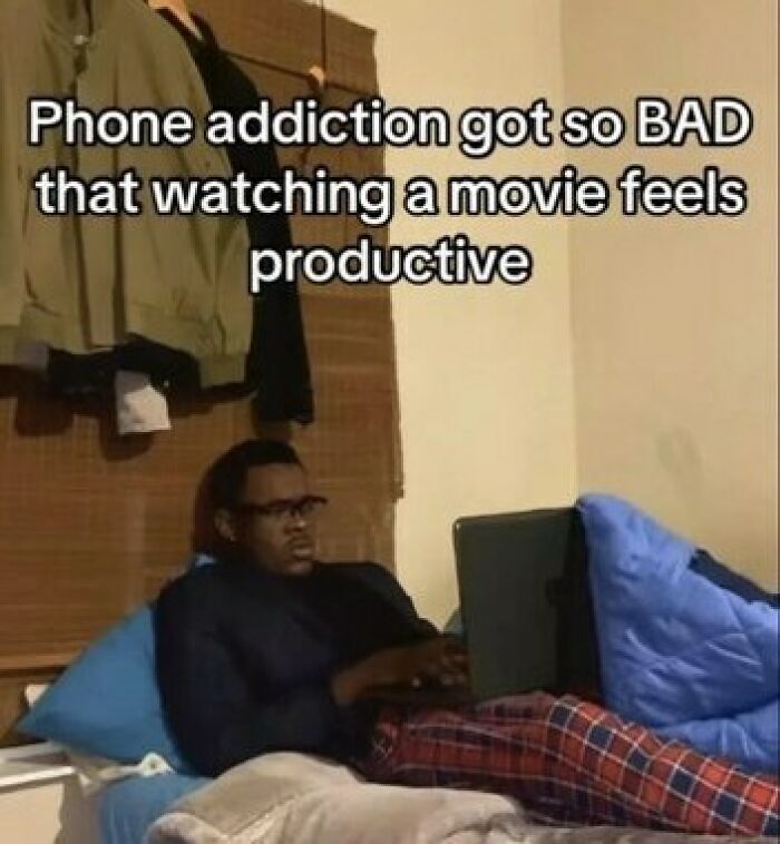 A funny meme about phone a*******n showing a man on a bed looking intensely at his laptop screen.