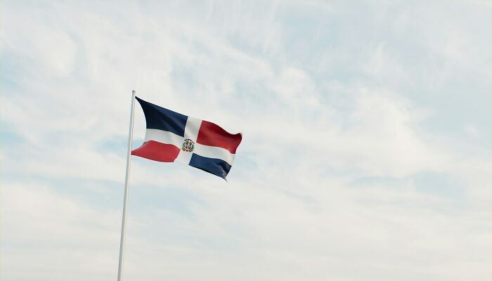 Wildly stupid things people said, the flag of the Dominican Republic waving against a light cloudy sky.