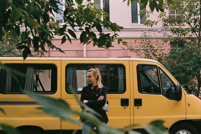 A woman standing next to a yellow van, representing legal transport and arguments heard in court.