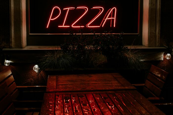 Outdoor pizza restaurant with neon pizza sign at night