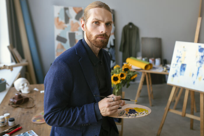 An artist holding a palette looks thoughtfully forward, capturing the reflection typical of divorced people