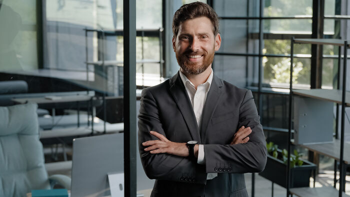 A smiling businessman with folded arms, symbolizing satisfying stories of letting a mistake speak for itself