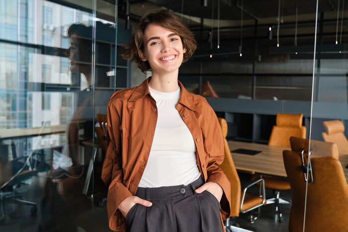 A confident businesswoman standing in a modern office, representing women who experience subtle sexism at work.