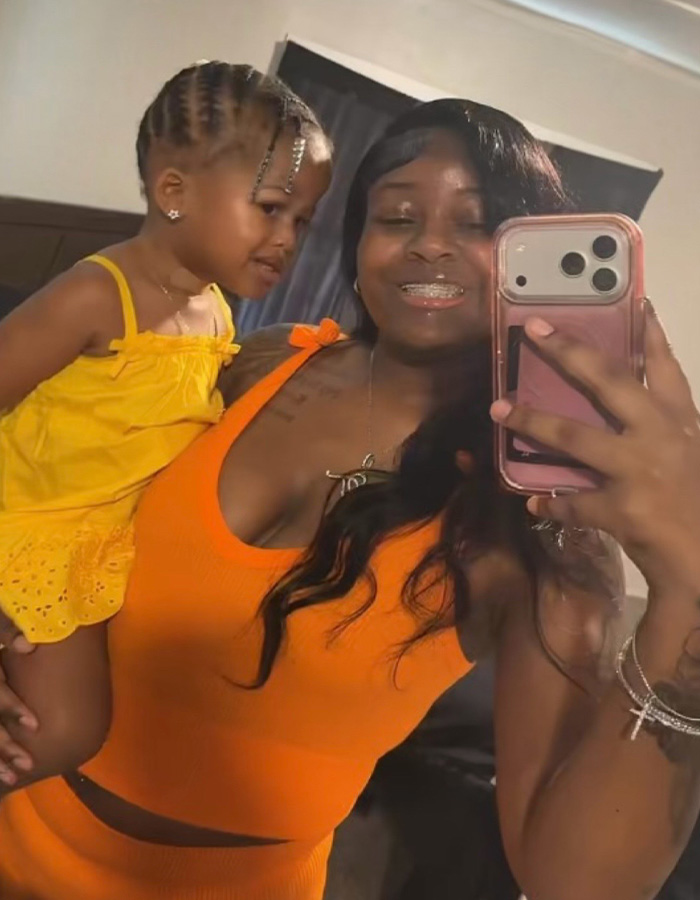 A smiling pregnant woman taking a selfie while holding her young child. A smiling pregnant woman taking a selfie while holding her young child.