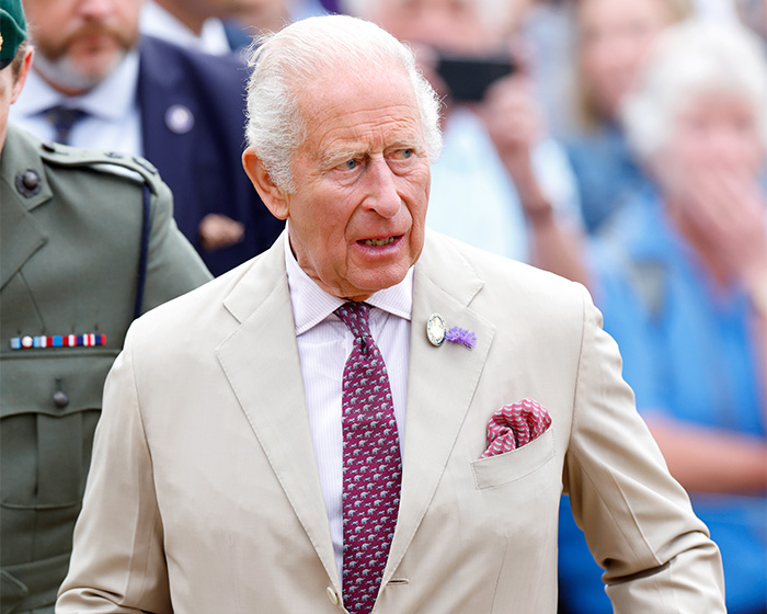 King Charles III attending a public event in a beige suit