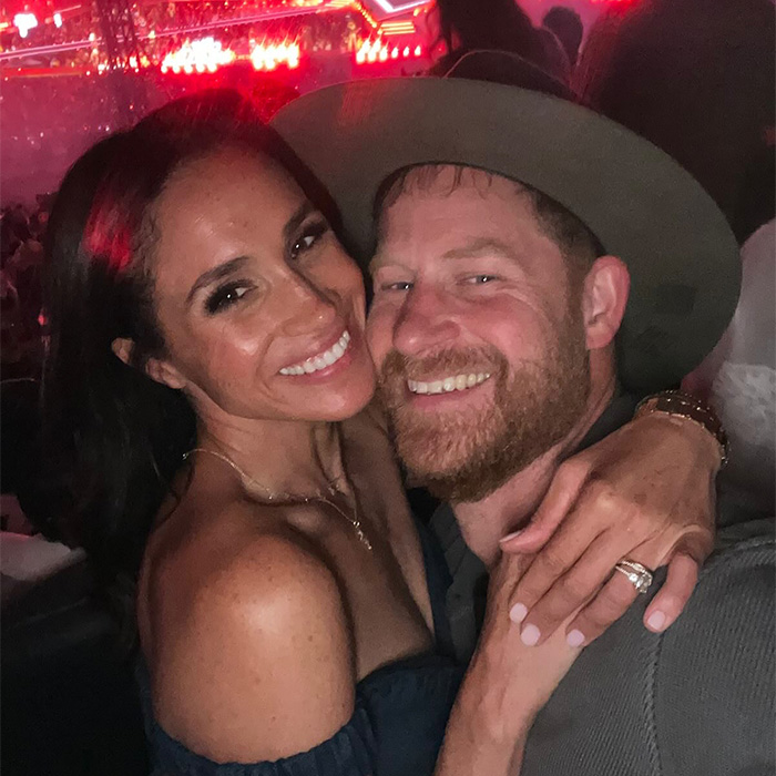 Close-up of Prince Harry and Meghan Markle smiling at a crowded event