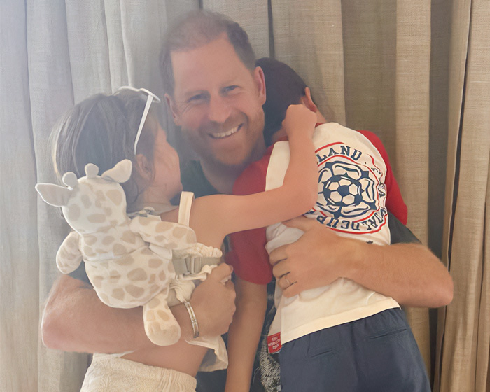 Prince Harry hugging children with joyful expression