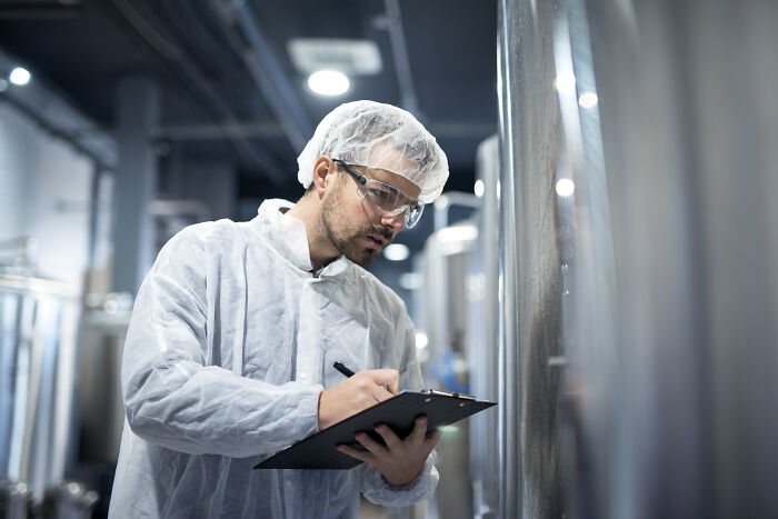 A professional in a cleanroom suit inspecting equipment, revealing industry secrets in manufacturing.