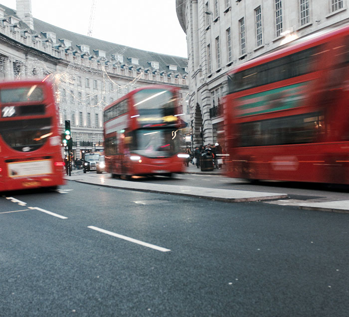 Blurred red double-decker buses in London, highlighting the Putney Pusher incident's location.