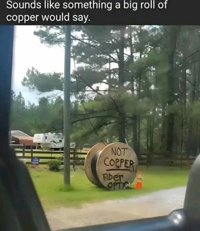 A large wooden spool with "NOT COPPER Fiber Optic" written on it, captured in a funny internet photo.