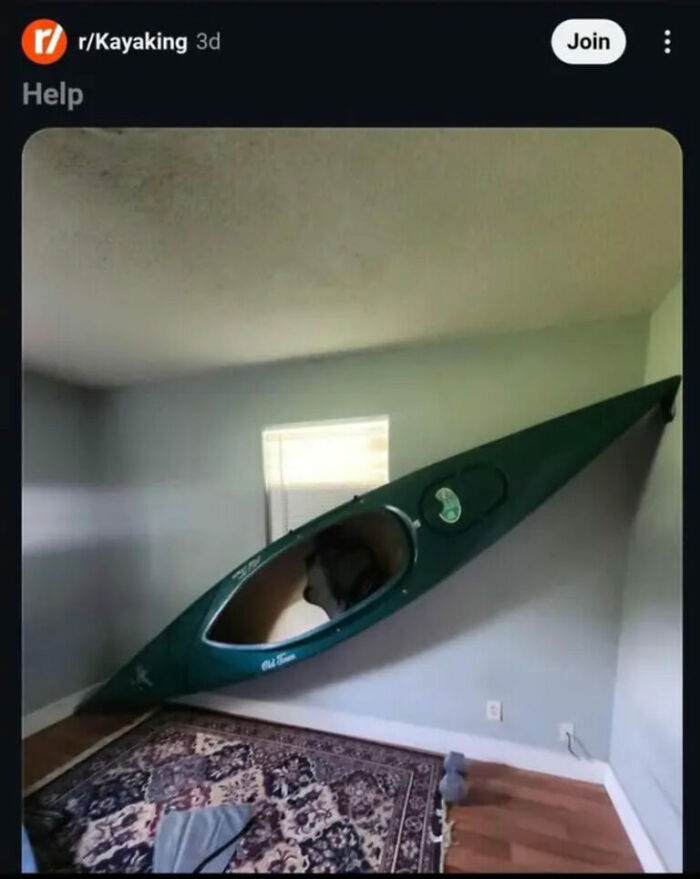 A hilarious photo from the Internet showing a green kayak awkwardly stuck between a wall and the ceiling in a room, needing help.
