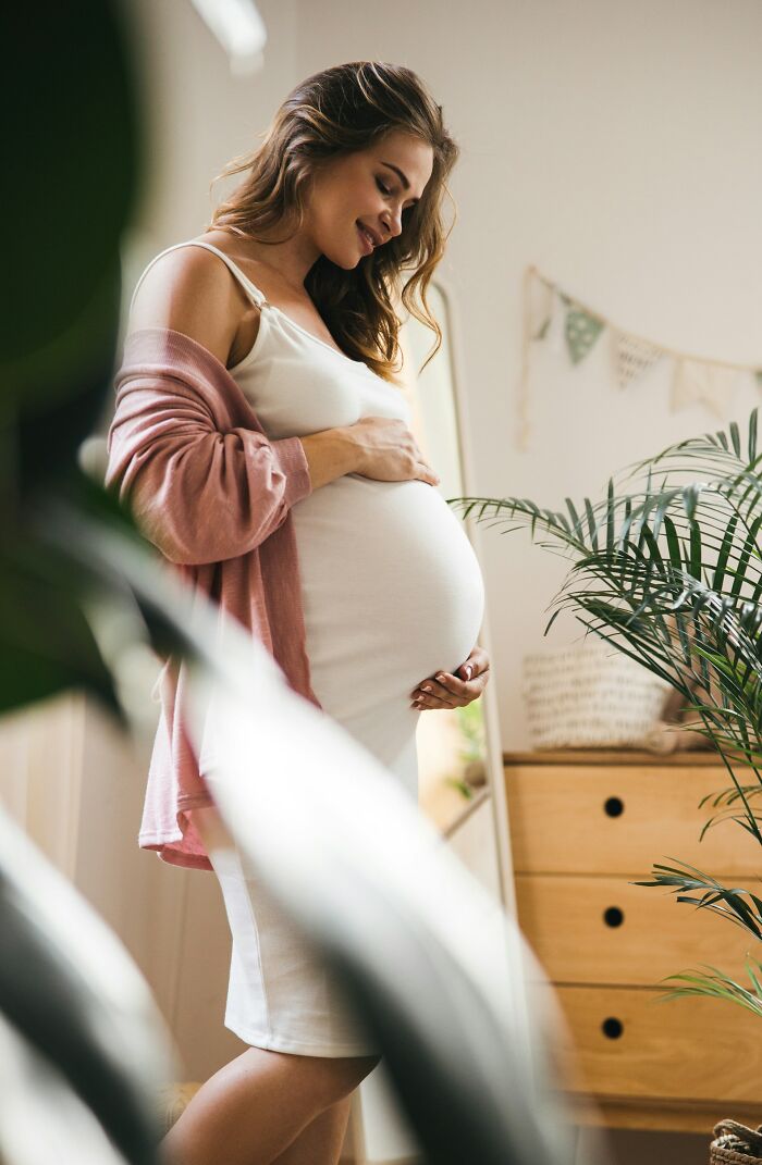 A smiling pregnant woman holding her belly, reflecting on how love alone isn't enough
