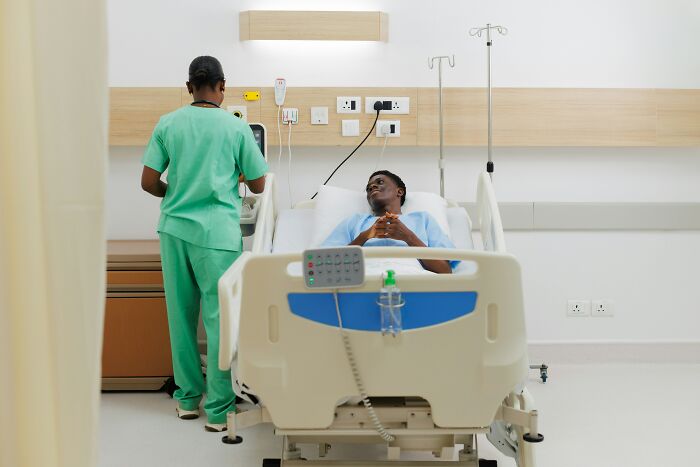 A patient in a hospital bed talking to a medical professional, telling stories that swear are 100% true.