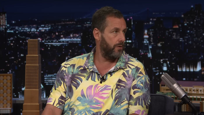 Adam Sandler on a talk show, sharing stories he swears are 100% true, not AI.
