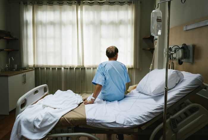 A man sitting on a hospital bed, contemplating stories he swears are 100% true, not AI.