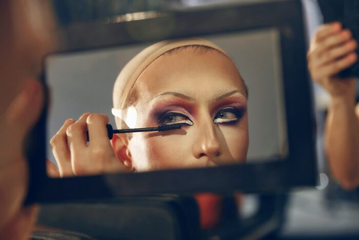 A person applying mascara, reflected in a mirror, for a story about being called liars for true stories.
