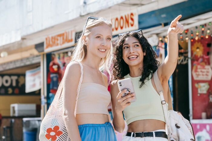Two young women smile and point into the distance, illustrating an idea for relationship revenge.