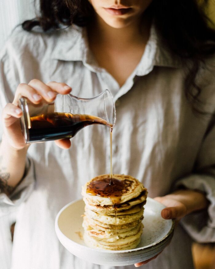 A woman pouring syrup on pancakes, symbolizing sweet relationship revenge stories.