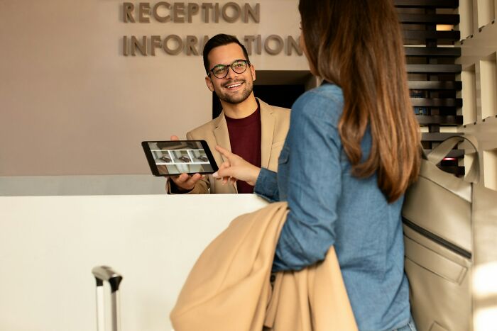 A hotel receptionist showing a tablet screen to a female guest, inspiring clever relationship revenge.