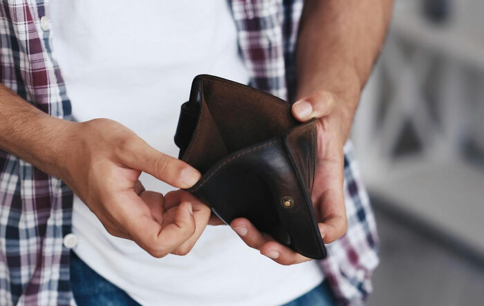 A man holding an empty wallet indicating a lack of money or issues with parents spending. A man holding an empty wallet indicating a lack of money or issues with parents spending.