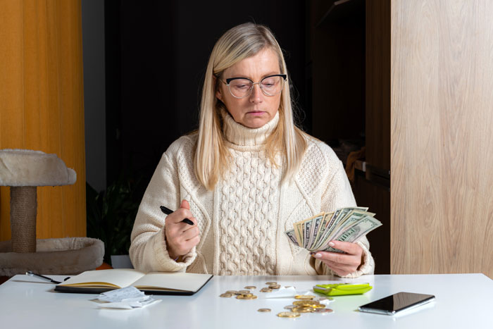 A senior mother counting cash representing parents spending as her millennial daughter controls the budget. A senior mother counting cash representing parents spending as her millennial daughter controls the budget.