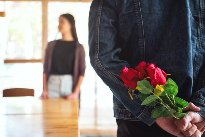 A man hides roses behind his back for a woman, symbolizing a complicated relationship or past relationship nightmare. A man hides roses behind his back for a woman, symbolizing a complicated relationship or past relationship nightmare.