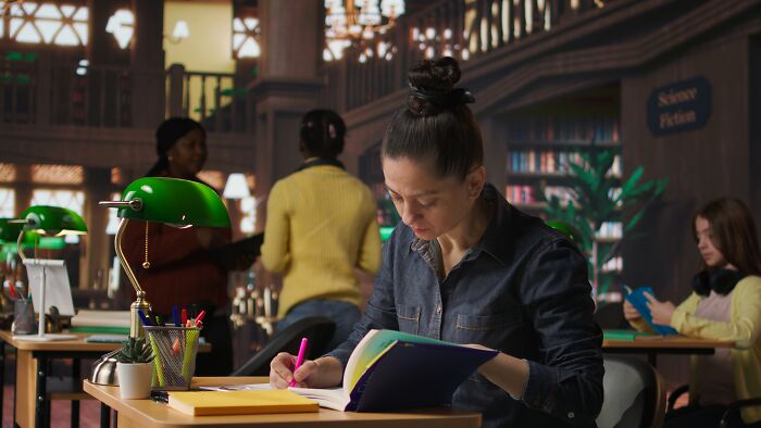 A woman studying in a library, surrounded by books, discovering industry secrets through research.