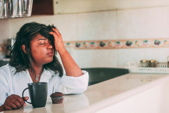 A tired woman in her 30s or 40s holding her head, experiencing energy levels and body changes.
