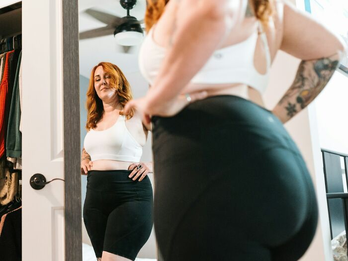 A woman looking at her reflection in the mirror, observing weirdest body changes in her 30s and 40s