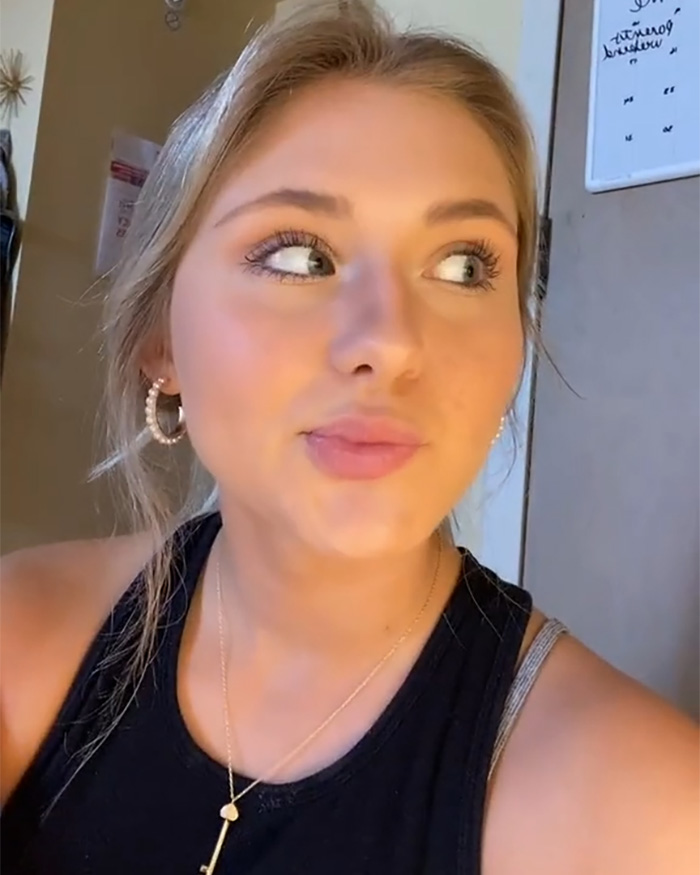 An attractive woman looks to the side, wearing a black tank top and necklace. She went viral for being spotted.