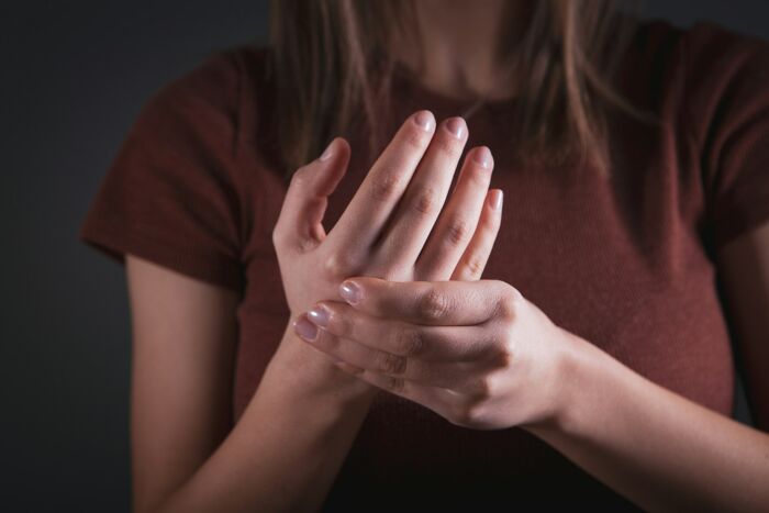 A close-up of a patient clutching their painful hand, reflecting a common reason strange patients visit medical staff