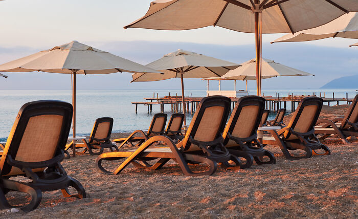 Empty lounge chairs with umbrellas on beach at vacation seaside