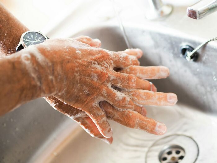 Close-up of soapy hands being washed under running water, highlighting medical practices.