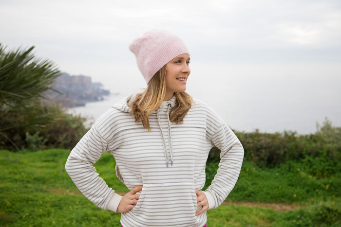 A happy young woman standing outdoors, displaying confident and relaxed body language.